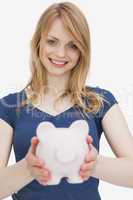 Blonde woman holding a piggy bank