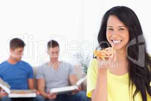 Woman smiling and looking at the camera as she holds pizza