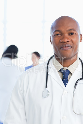 Young and confident doctor grinning in front of his medical team