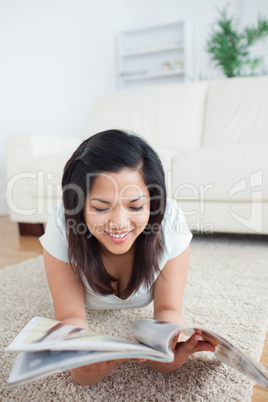 Woman reading a magazine as she lays on the floor