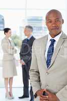 Businessman wearing a suit and crossing his hands with his team