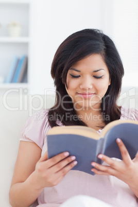 Woman sits on a couch while reading a book