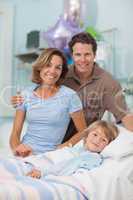 Child lying on a medical bed next to his parents