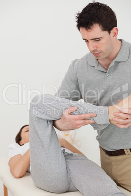 Brunette physiotherapist stretching the leg of a patient