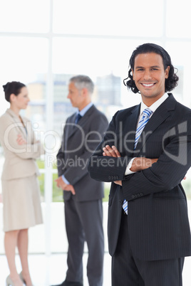 Young smiling executive standing upright in front of two busines