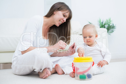 Mother sitting next to a baby playing