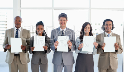 Smiling business team standing upright side by side while showin
