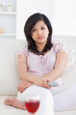 Woman sitting on a couch while crossing her arms and holding a t