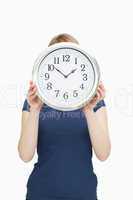 Blonde woman holding a clock in front of her face