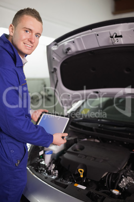 Smiling mechanic testing an engine with a tablet computer