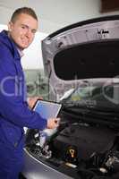 Smiling mechanic testing an engine with a tablet computer