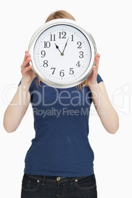 Woman holding a clock in front of her face