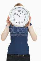 Woman holding a clock in front of her face