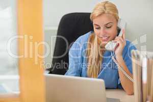 Blonde nurse calling next to a laptop