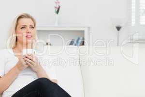 Woman sitting on a sofa with cup in her hands