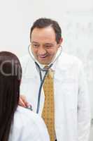 Smiling doctor auscultating a woman
