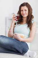 Woman holding a glass of red wine and a bowl of popcorn