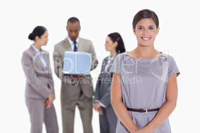 Woman smiling with business team in the background with a laptop