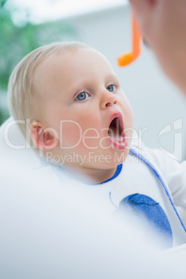 Baby on a high chair with opened mouth