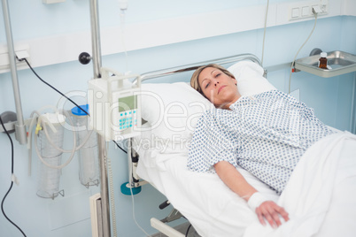 Female patient lying on a medical bed with half-closed eyes