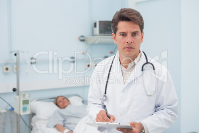 Doctor writing while holding a chart