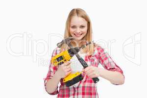 Woman holding an electric screwdriver and a hammer