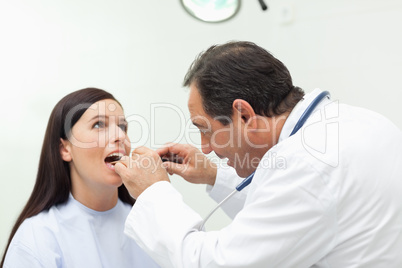 Doctor looking at the mouth of his patient