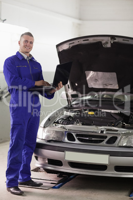 Mechanic standing while holding a computer