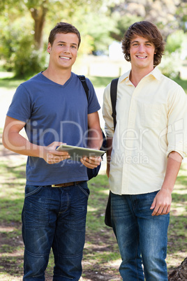 Portrait of two smiling male students with a touch pad