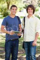 Portrait of two smiling male students with a touch pad