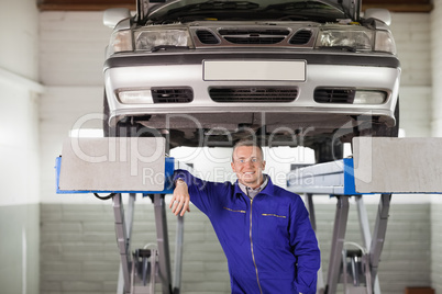 Smiling mechanic below a car