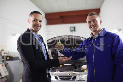 Mechanic smiling while giving car key to a man