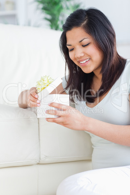 Woman opening a gift box while standing on her knees in front of