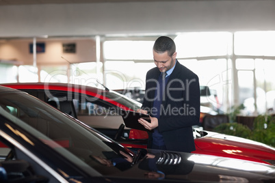 Man writing on a clipboard beside a car