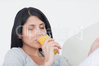 Woman closing her eyes while drinking a glass of orange juice