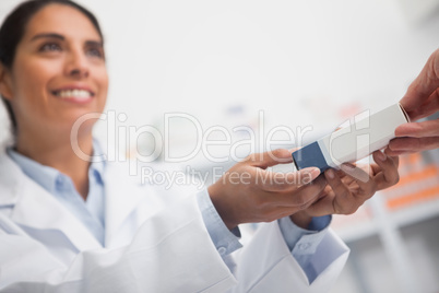 Close up of a smiling pharmacist giving a box to someone