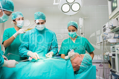 Nurse drying forehead of a concentrated surgeon