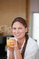 Woman drinking orange juice while smiling