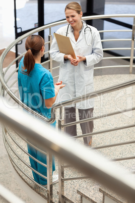 Doctor holding a file while talking to a nurse