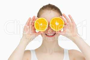 Smiling woman placing oranges on her eyes