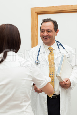 Doctor shaking the hand of a patient while holding a file