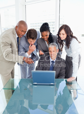 Four young executives attentively looking at the laptop screen