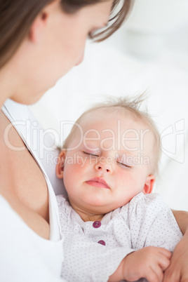 Cute baby sleeping in the arms of her mother