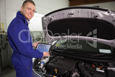 Mechanic looking at camera while holding a tablet computer