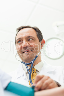 Smiling doctor measuring the blood pressure of his patient