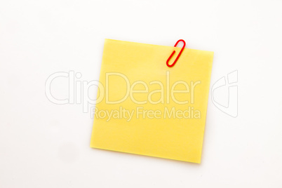 Yellow adhesive note with a paperclip