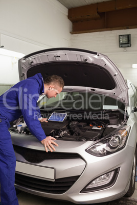 Concentrated mechanic looking at a car engine