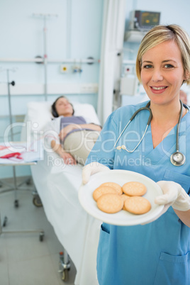 Smiling nurse holding a biscuits plate