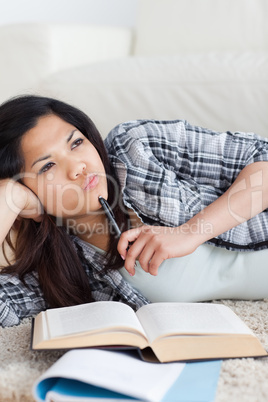 Close-up of a woman thinking while holding a pen and a book