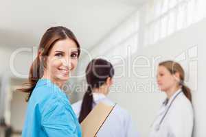 Smiling nurse  while standing in a hallway with a patient and a